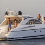 Yate mediano con zona de cama para tumbarse y grupo de chicos disfrutando a bordo